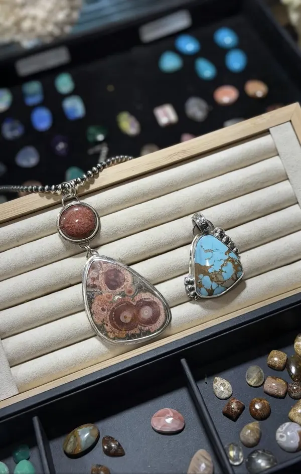 Three finished sterling pendants on a tray above the stone drawers